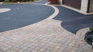 Driveway paved with asphalt and pavers design.